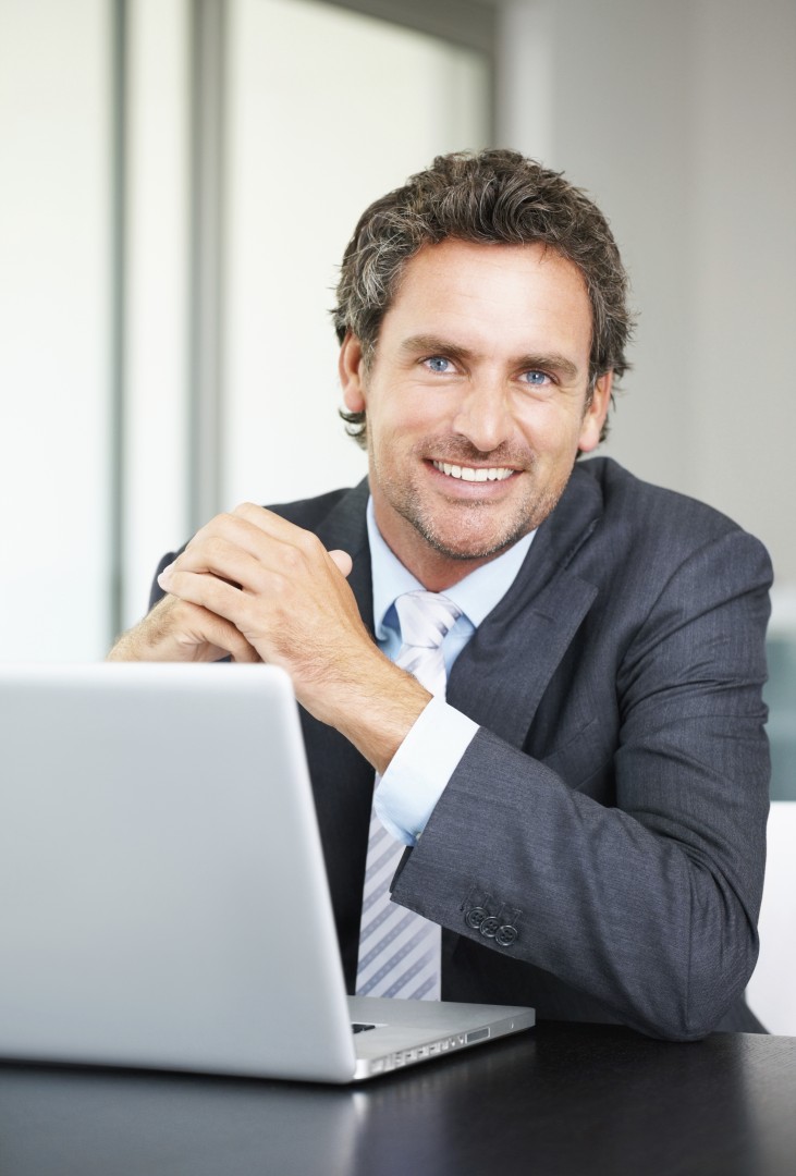 Portrait of business man using laptop and giving you a warm smile